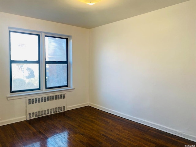 spare room with dark hardwood / wood-style floors and radiator