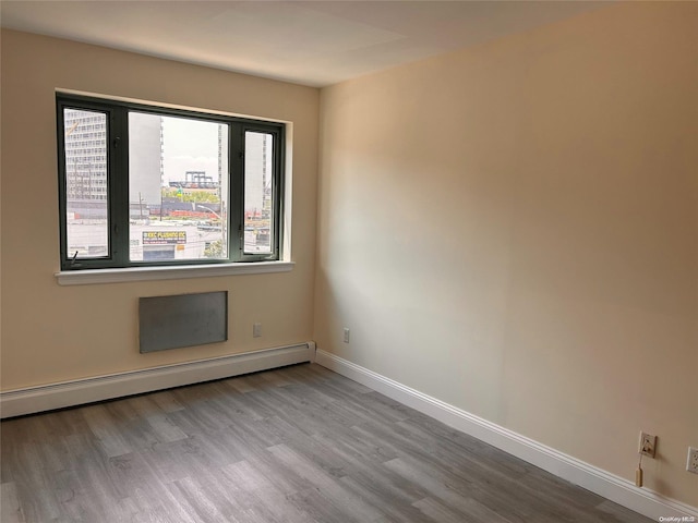 unfurnished room featuring light hardwood / wood-style floors and a baseboard heating unit