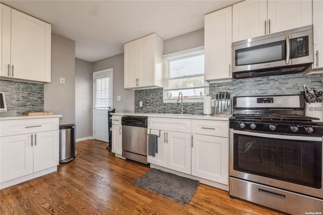 kitchen with white cabinetry, sink, stainless steel appliances, tasteful backsplash, and dark hardwood / wood-style flooring