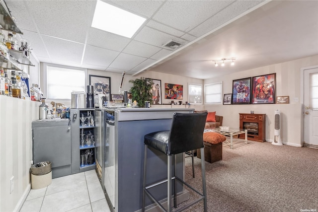 kitchen featuring a breakfast bar, a paneled ceiling, kitchen peninsula, and light tile patterned flooring