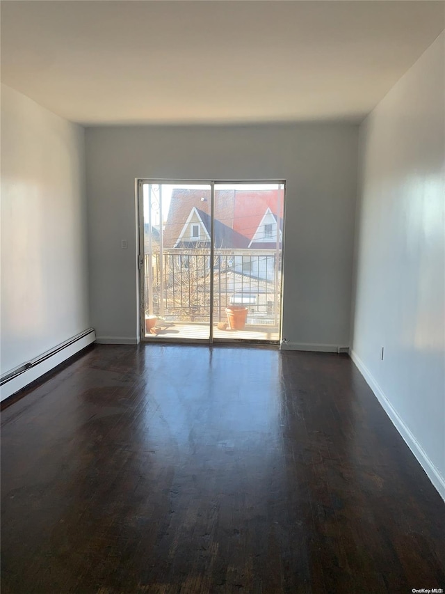 empty room featuring dark wood-type flooring and a baseboard heating unit