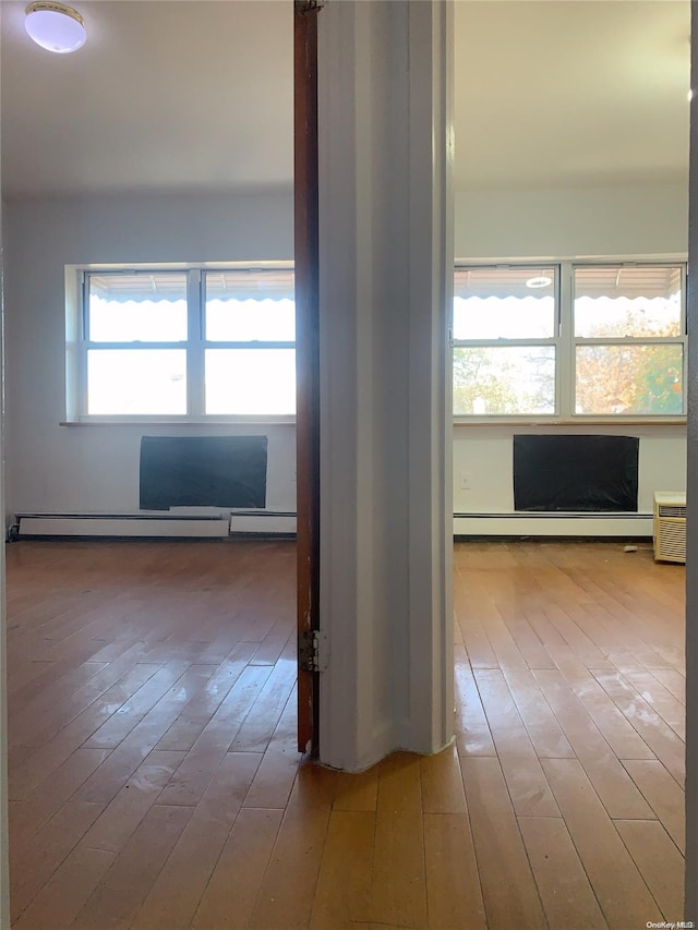 corridor featuring hardwood / wood-style flooring, an AC wall unit, and baseboard heating