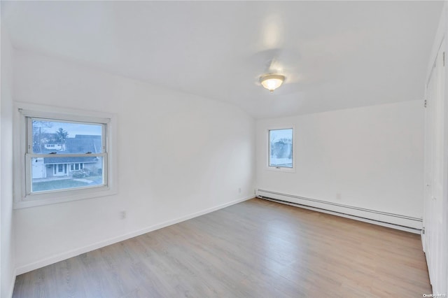 unfurnished room with baseboard heating, a wealth of natural light, and light wood-type flooring