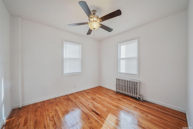 spare room with ceiling fan, radiator heating unit, and light hardwood / wood-style flooring