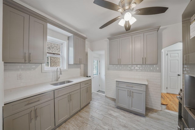 kitchen with tasteful backsplash, light hardwood / wood-style flooring, gray cabinetry, and sink