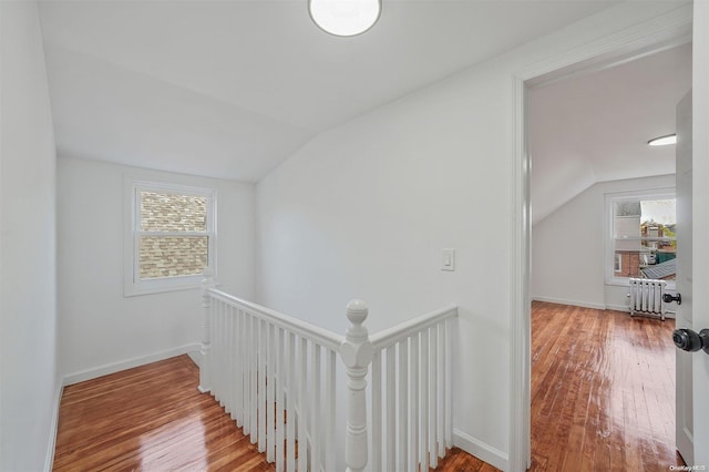 corridor featuring radiator heating unit, hardwood / wood-style floors, and vaulted ceiling