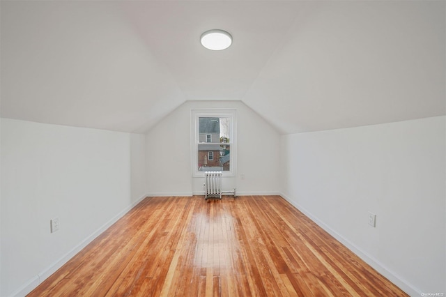 additional living space with light hardwood / wood-style floors, radiator, and vaulted ceiling