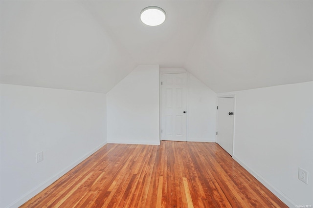 additional living space with light hardwood / wood-style floors and vaulted ceiling