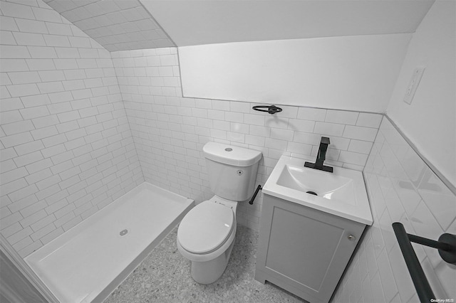 bathroom with tiled shower, vanity, toilet, and tile walls