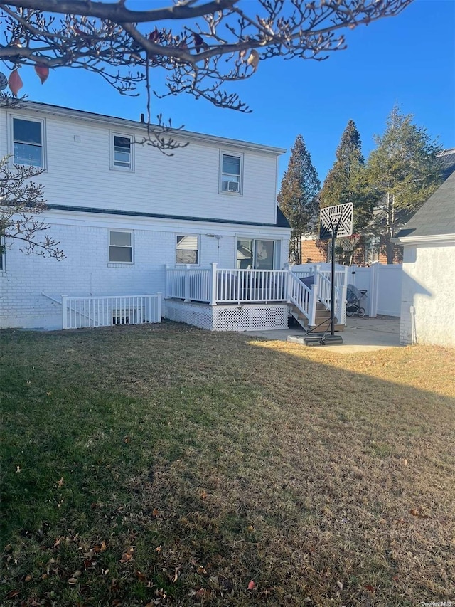 rear view of house featuring a deck and a lawn