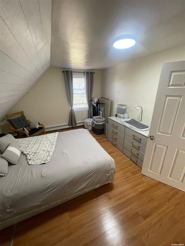 bedroom featuring light hardwood / wood-style flooring, a baseboard radiator, lofted ceiling, and sink