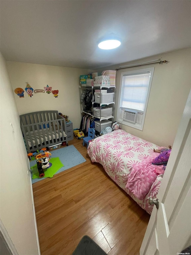 bedroom featuring wood-type flooring and cooling unit