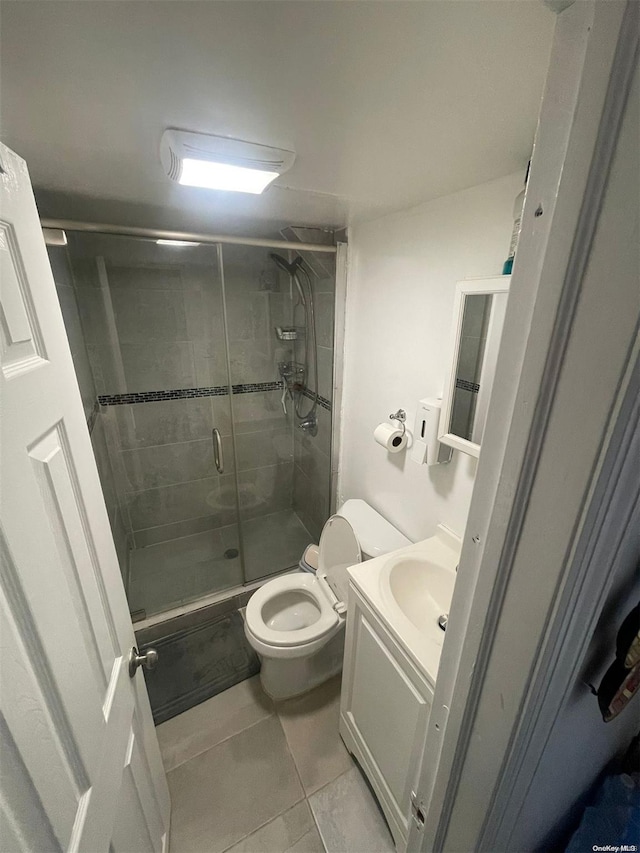 bathroom featuring tile patterned flooring, vanity, toilet, and an enclosed shower