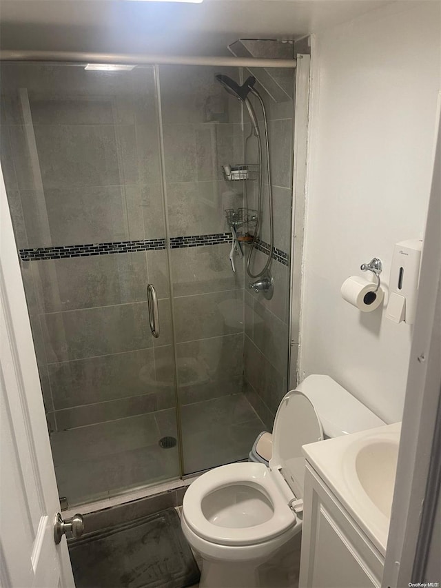 bathroom with vanity, a shower with shower door, and toilet