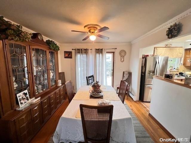 dining space featuring crown molding, ceiling fan, wood-type flooring, and a baseboard radiator