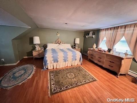 bedroom featuring hardwood / wood-style floors and a baseboard heating unit