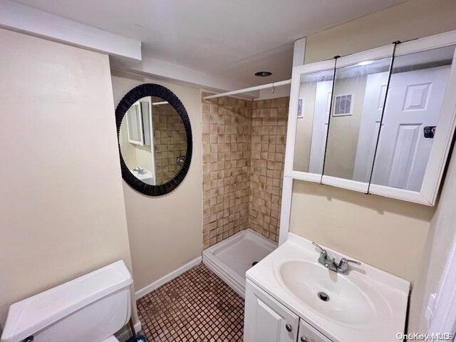 bathroom featuring a tile shower, tile patterned floors, vanity, and toilet