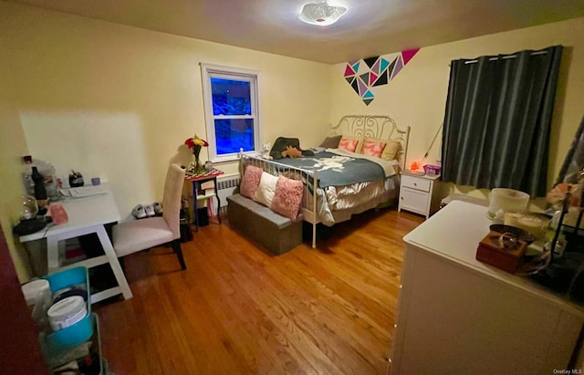 bedroom featuring wood-type flooring and radiator heating unit