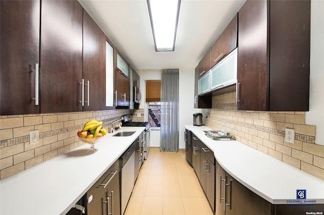 kitchen with backsplash, sink, appliances with stainless steel finishes, dark brown cabinets, and light tile patterned flooring