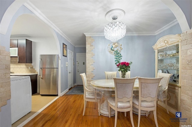 dining space with light hardwood / wood-style floors, an inviting chandelier, washer / clothes dryer, and ornamental molding