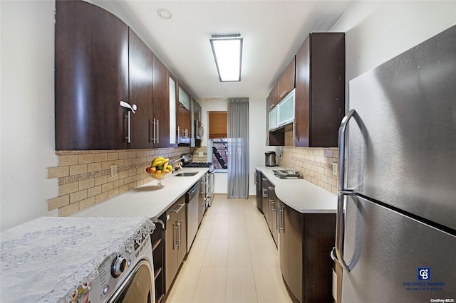 kitchen with dark brown cabinetry, sink, stainless steel appliances, decorative backsplash, and light tile patterned floors