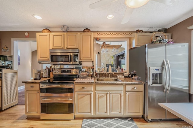 kitchen featuring a textured ceiling, stainless steel appliances, light hardwood / wood-style floors, sink, and ornamental molding