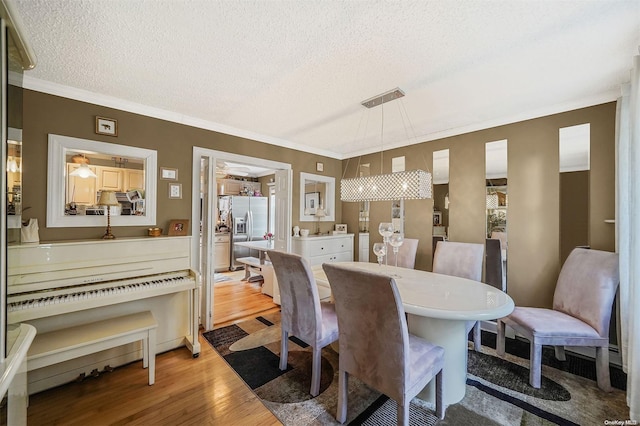 dining space with a textured ceiling, light hardwood / wood-style flooring, and ornamental molding