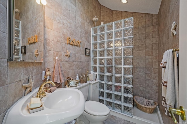 bathroom with toilet, a shower, tile walls, sink, and lofted ceiling