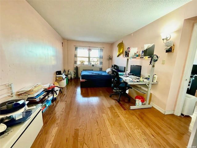 bedroom with a textured ceiling and light hardwood / wood-style flooring