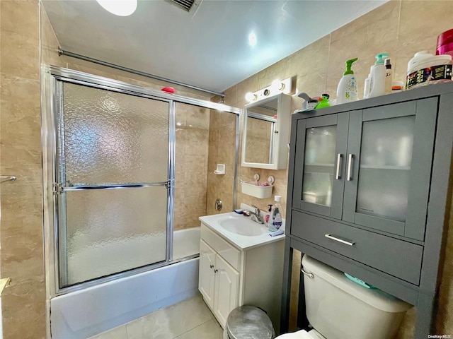 full bathroom featuring enclosed tub / shower combo, tile patterned floors, toilet, vanity, and tile walls