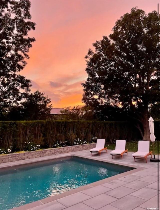 pool at dusk featuring a patio