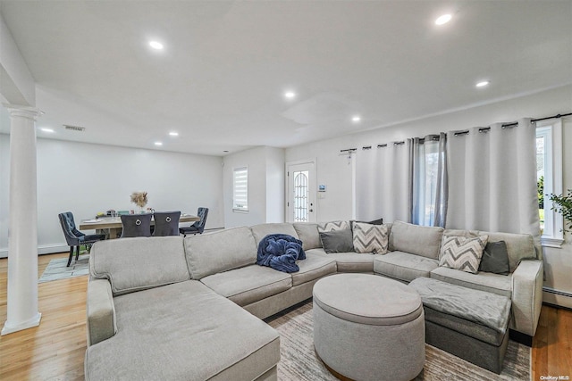 living room featuring hardwood / wood-style flooring, plenty of natural light, and decorative columns