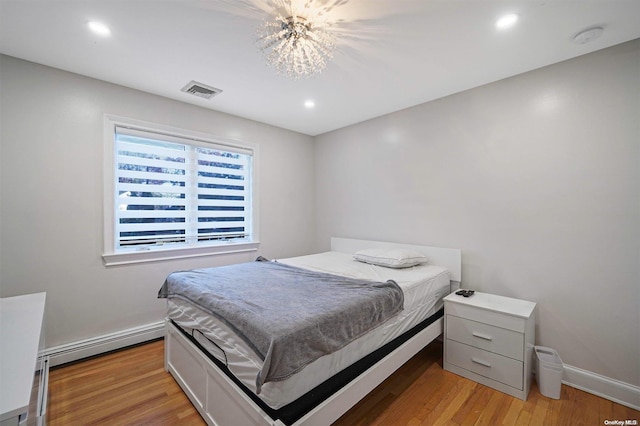 bedroom with light hardwood / wood-style flooring and a baseboard heating unit