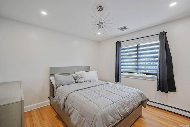 bedroom featuring light wood-type flooring and a baseboard heating unit