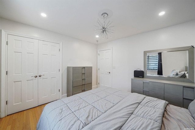 bedroom featuring a notable chandelier, light hardwood / wood-style floors, and a closet