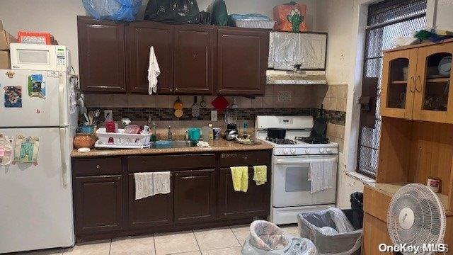 kitchen featuring sink, white appliances, decorative backsplash, light tile patterned floors, and exhaust hood