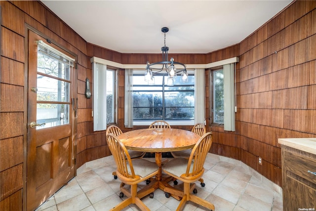 dining space featuring wooden walls and an inviting chandelier