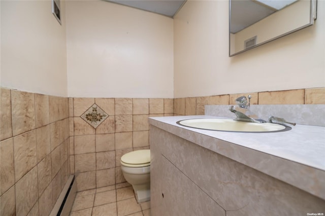 bathroom with vanity, tile patterned floors, toilet, baseboard heating, and tile walls