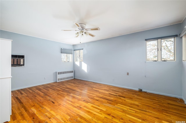 spare room with ceiling fan, light hardwood / wood-style floors, radiator, and a wall mounted AC