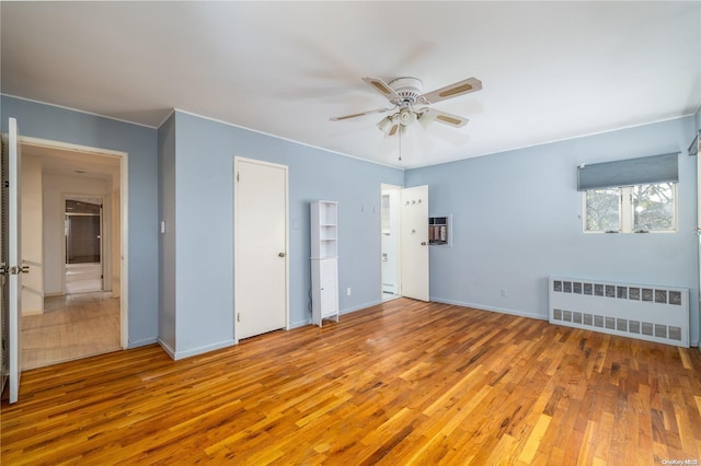 unfurnished bedroom with ceiling fan, light wood-type flooring, and radiator