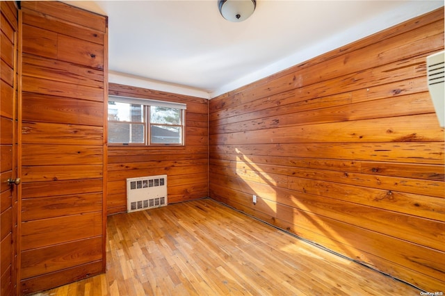 unfurnished room featuring wooden walls and light hardwood / wood-style flooring