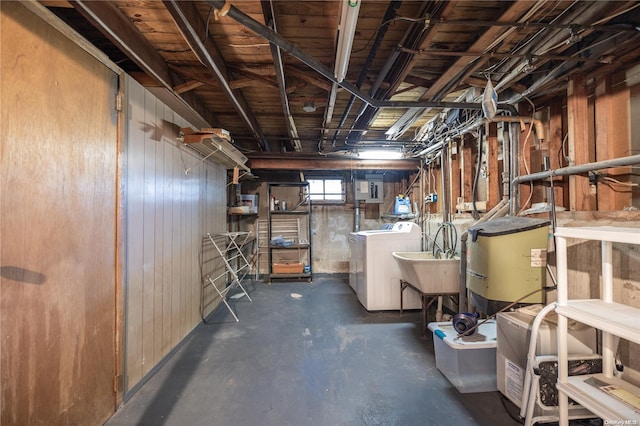 basement with wooden walls, washer and clothes dryer, and sink