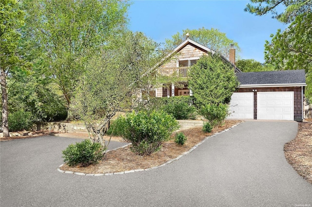 view of property hidden behind natural elements with a balcony and a garage