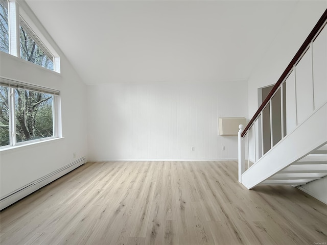 unfurnished living room featuring light wood-type flooring, vaulted ceiling, and baseboard heating