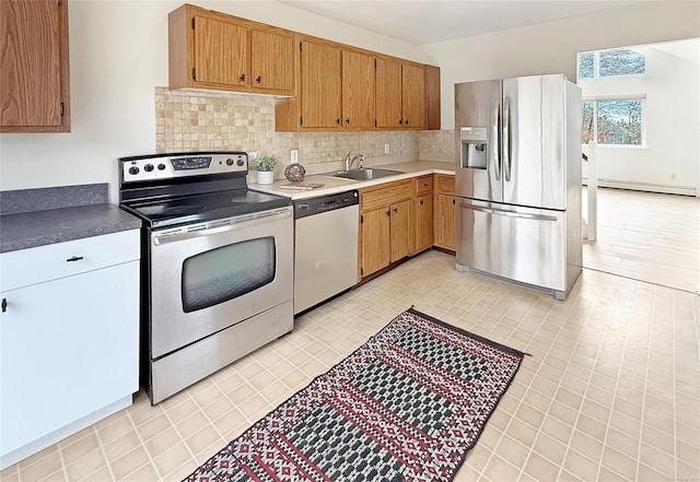 kitchen featuring sink, a baseboard radiator, tasteful backsplash, and stainless steel appliances