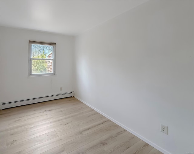 unfurnished room featuring baseboard heating and light hardwood / wood-style flooring