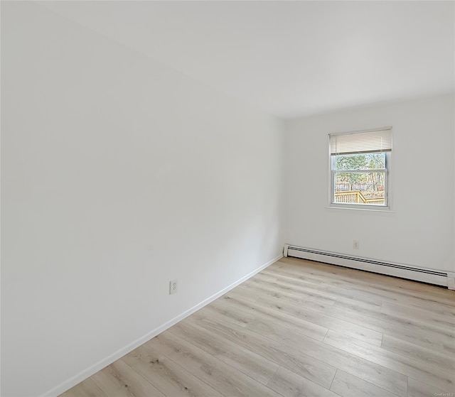 empty room with light hardwood / wood-style floors and a baseboard heating unit