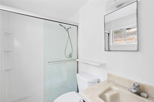 bathroom featuring a shower with door, toilet, and vanity