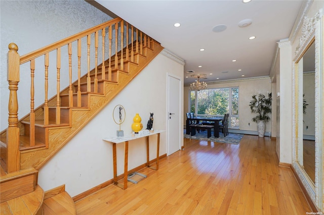 stairway featuring wood-type flooring, an inviting chandelier, and ornamental molding