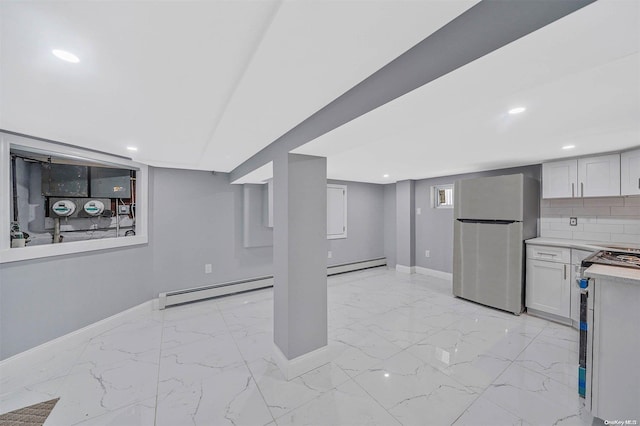 basement with a baseboard radiator and stainless steel refrigerator